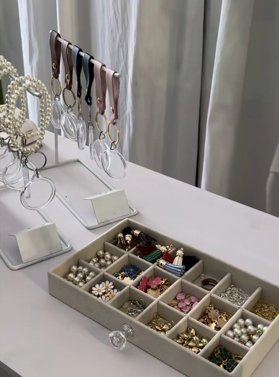 Acrylic keychains with wrist straps beside a selection of colorful charms and tassels