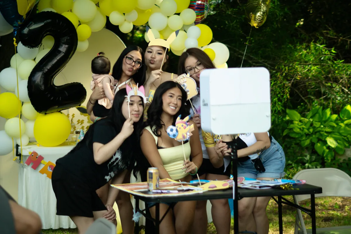 Guests posing with props at an outdoor birthday party